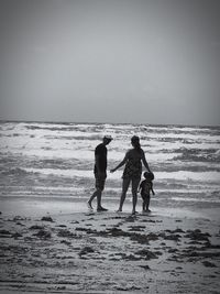 People walking on beach against sea