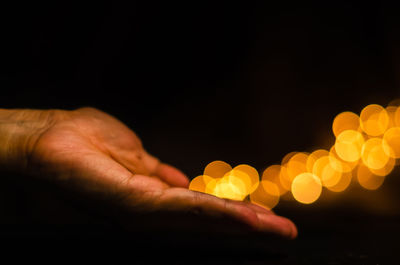 The hand releases yellow round shape bokeh light on black background.