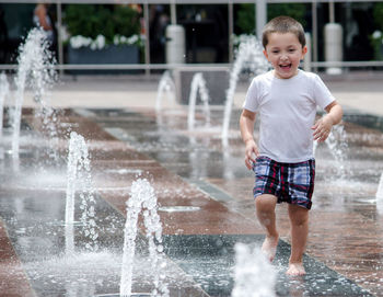 Hispanic boy running in a city outdoor fountain