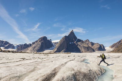 Mountaineer crosses a river on the caribou glacier, baffin island