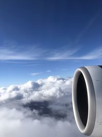 View out of airplane window flying over clouds against blue sky