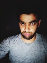 Portrait of young man against black background