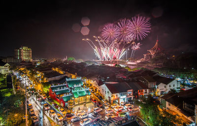 Firework display in city against sky at night