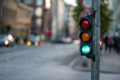 Blurred view of city traffic with traffic lights, in the foreground a semaphore with a green light