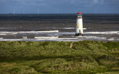 Lighthouse by sea against sky