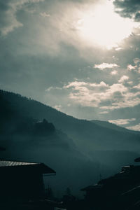 Scenic view of silhouette houses and mountains against sky