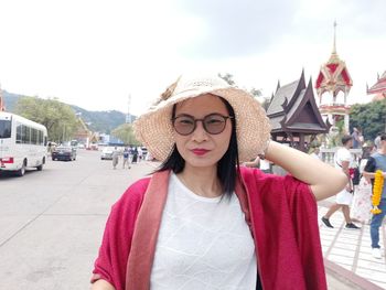 Portrait of mature woman wearing hat and eyeglasses while standing on road