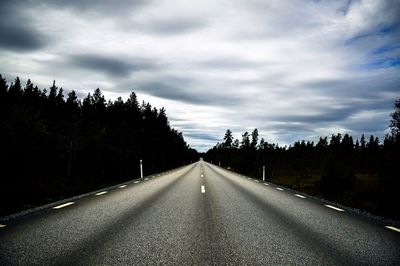 Surface level of road along trees against sky