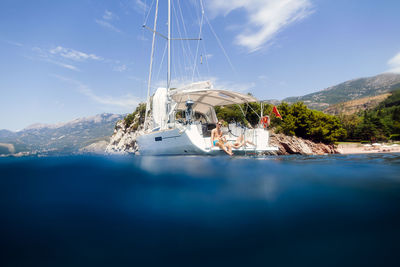 Low angle view of couple on sailboat in sea against sky