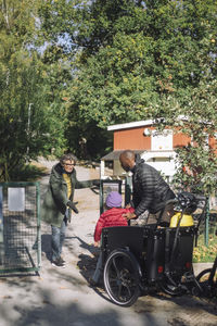 Female teacher assisting children while entering at kindergarten