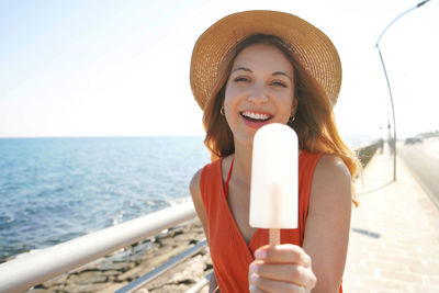 Beautiful young woman offers a lemon popsicle at the camera on summer
