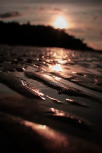 Surface level of sea against sunset sky