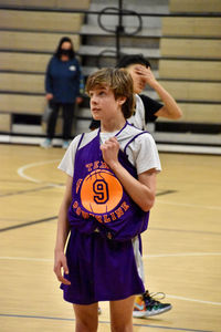 Full length of boy playing basketball on indoor court 