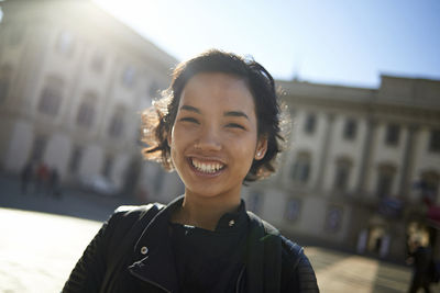 Portrait of smiling woman standing against building in city