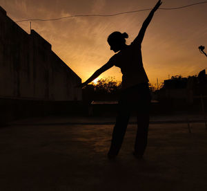 Silhouette man playing soccer against sky during sunset