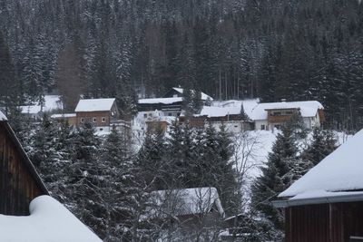 Snow covered houses by trees and buildings in background
