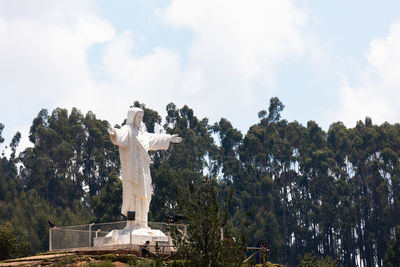 Low angle view of statue against trees and sky