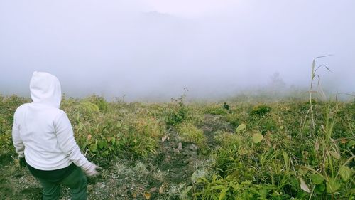 High angle view of young woman standing on field during foggy weather