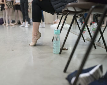 Low section of ballet dancer sitting on chair at ballet studio