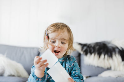 Cute girl playing with plastic cups while sitting at home