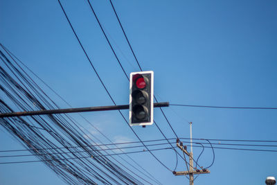 Low angle view of electricity pylon against clear blue sky