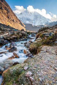 Scenic view of stream flowing by mountains