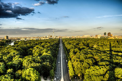 Aerial view of city street amidst trees against sky