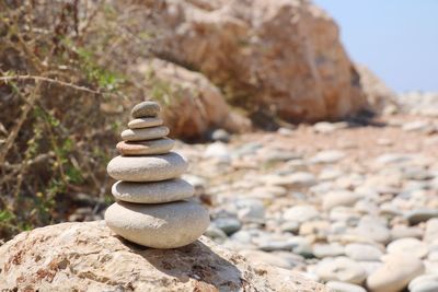 Stacked pebbles on rock at beach during sunny day