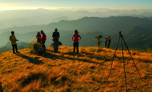 People standing on field by mountains against sky