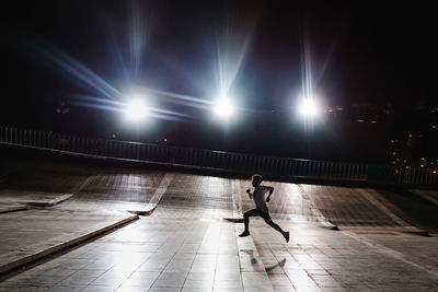 Woman walking on illuminated street at night