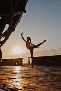 Silhouette teenage girl dancing against sky during sunset