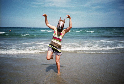 Man in horse head standing on beach