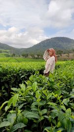 Woman holding plant standing on field