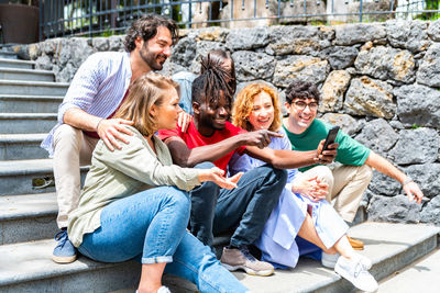 Friends using phone while sitting on steps