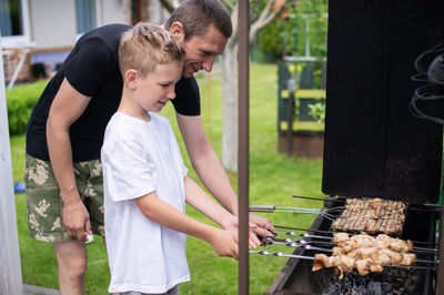 Side view of young man preparing food on barbecue grill