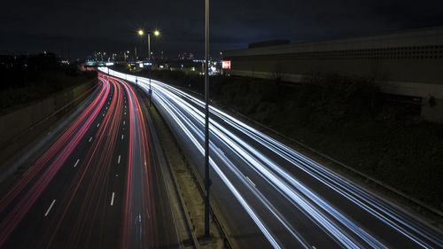 Light trails on city street against sky at night