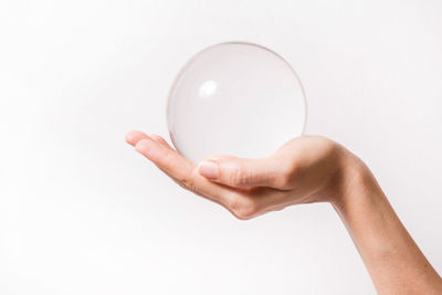 Midsection of person holding crystal ball against white background