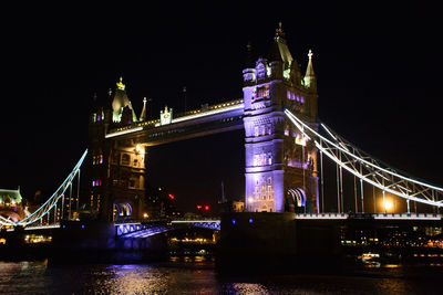 Illuminated bridge over river at night