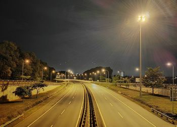 Illuminated street lights against sky at night