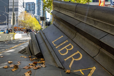 Text on yellow street by footpath in city