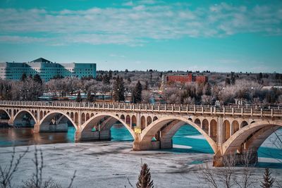 Arch bridge over river against sky in city