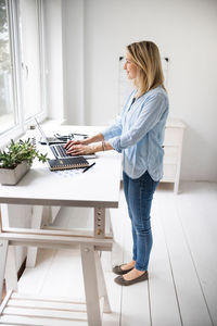 Side view of woman using mobile phone at home