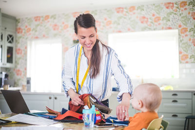 Smiling working mother caring daughter while holding fabric swatch in home office