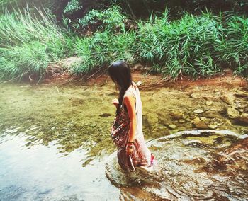 Full length side view of young woman standing in a lake