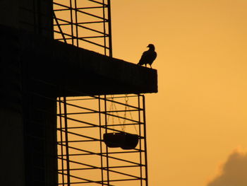 Low angle view of man working against orange sky