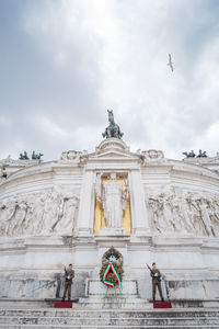 Low angle view of angel statue against cloudy sky