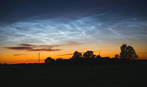 Silhouette trees on field against sky during sunset