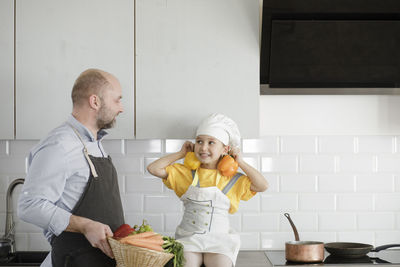 Rear view of people standing in kitchen