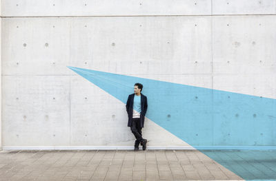 Full length of man standing on concrete wall