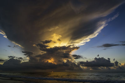 Scenic view of sea against dramatic sky during sunset